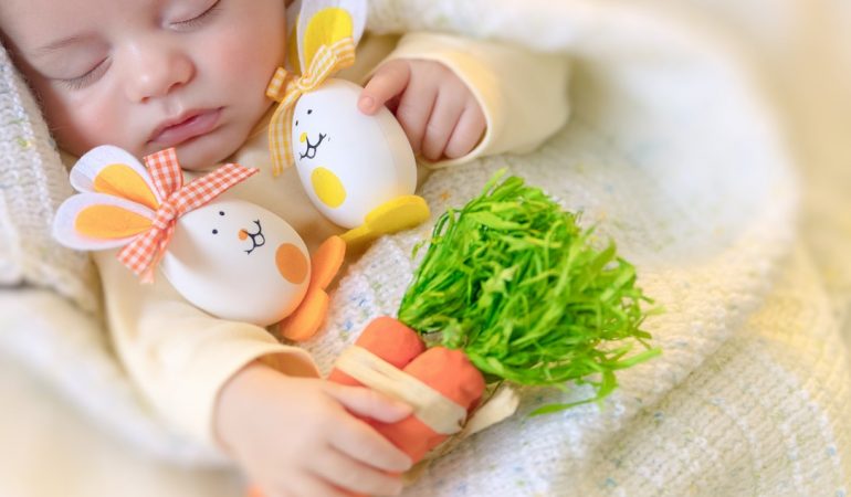 Happy easter, portrait of a cute little baby sleeping at home with his toys, decorated Easter eggs rabbits, calm pretty child napping